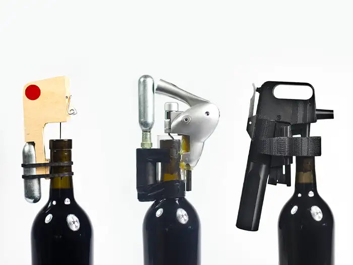 Three wine bottle openers displayed on dark bottles: one corkscrew style, one lever-style, and one pressurized opener.