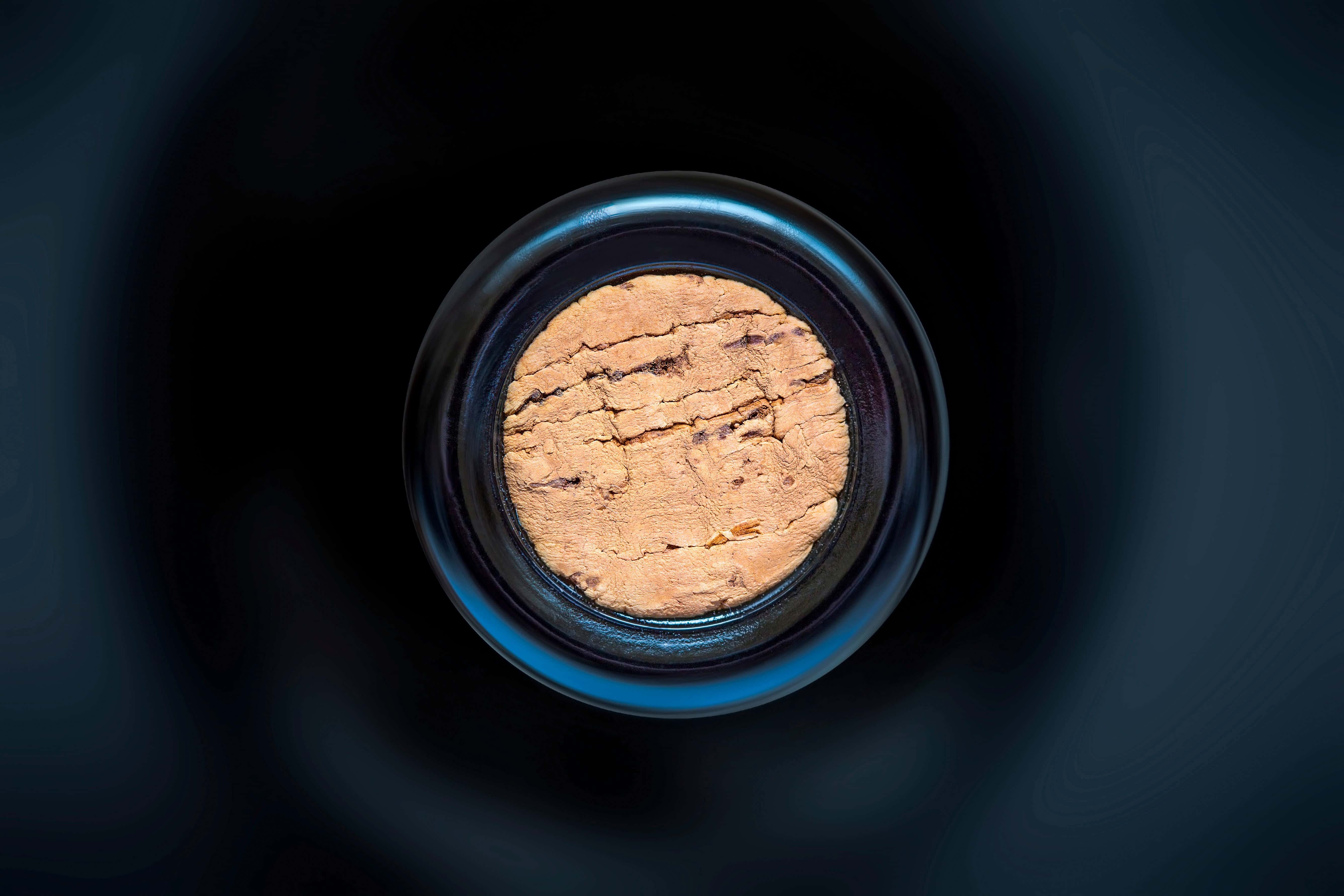 Top-down view of a natural cork inside a wine bottle, showcasing texture and detail against a dark background.