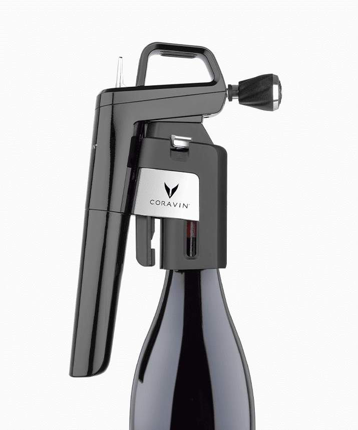 Coravin wine preservation system attached to a dark wine bottle, designed for pouring without removing the cork.