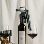 Coravin wine aerator on a bottle of 2017 Lowe Zinfandel, with two glasses of red wine and a candle in a dining setting.